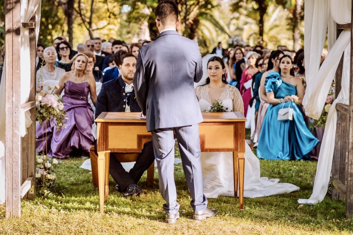 Cerimonia all'aperto: gli sposi al tavolo e gli invitati intorno